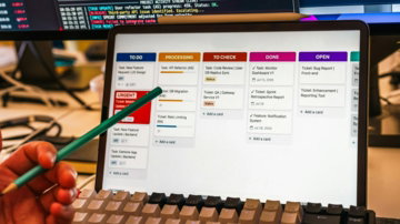 A person pointing at a digital kanban board on a tablet screen